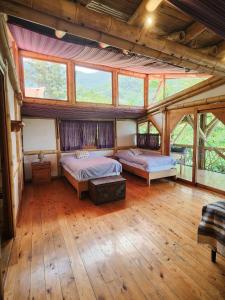 two beds in a room with wooden floors and windows at Bambu Guest House in Tzununá