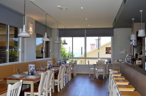 a restaurant with wooden tables and white chairs at A Fontiña in Montalvo