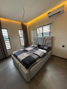 a bedroom with a bed in a room with windows at Boa Vista villa in Paramaribo