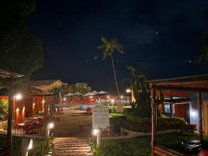 a night view of a resort with a palm tree at Bangalô com Quarto, Sala, Varanda in Maceió