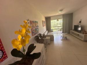 a living room with a vase with yellow flowers in it at Bangalô com Quarto, Sala, Varanda in Maceió