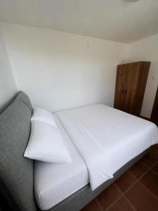 a bed with white sheets and pillows in a room at Darinka in Ulcinj