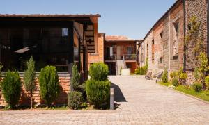 a brick building with a door and bushes next to a sidewalk at Hotel Ticiani 15 in Kutaisi
