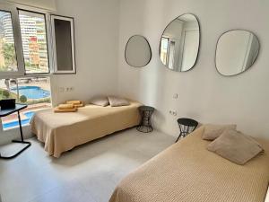 two beds in a room with mirrors on the wall at Front Line on the beach in Calpe +20 photos