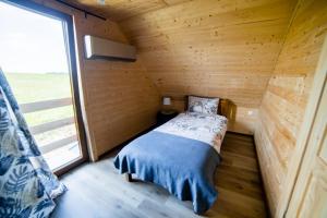 a small bed in a wooden room with a window at Domek na Bieszczadach Domek na Bani 2 in Łukowe