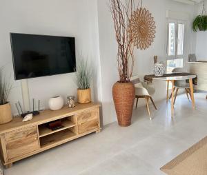 a living room with a tv and a vase with plants at Front Line on the beach in Calpe