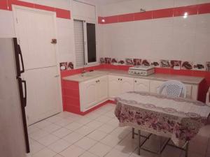 a red and white kitchen with a table and a refrigerator at Appartement Ezzdine sfaxi in Kelibia