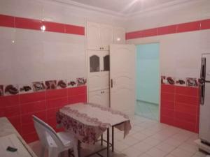 a kitchen with a table and a red wall at Appartement Ezzdine sfaxi in Kelibia +4 photos