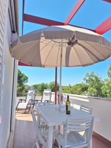 a white table with a bottle of wine and an umbrella at Onde e Relax D&D in Marina di Bibbona