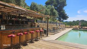 a bar with red stools next to a swimming pool at Suite piscine in Valensole