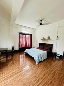 a bedroom with a bed and a wooden floor at The Quiet Lantern Homestay in Sibsāgar