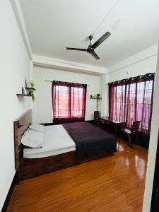 a bedroom with a bed and a desk and windows at The Quiet Lantern Homestay in Sibsāgar