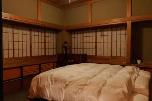 a bedroom with a large white bed with windows at Tokyo Sake House in Ome