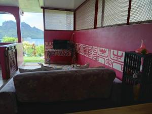 a living room with a couch and a red wall at CHEZ ALIZHIA in Nuku Hiva
