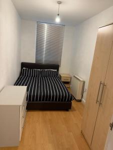 a bedroom with a black bed and a window at Central 2 bed large apt M1 area in Manchester