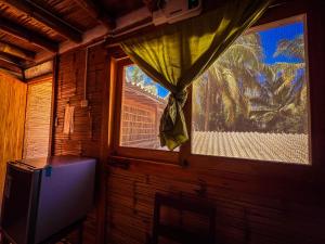 ein Zimmer mit einem Fenster mit Vorhang und einem Fernseher in der Unterkunft La Posada in Máncora