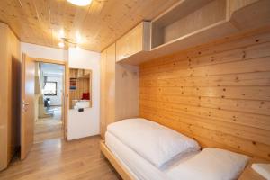 a bedroom with a wooden wall with a bed in it at Césa Marta in Canazei