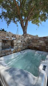 a hot tub with a tree in a stone wall at Pyrgianos Suites - Private Jacuzzi in Glinado Naxos