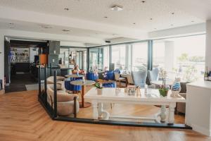 a lobby with a table and chairs and people at Le Thalassa Hôtel & Spa in Camaret-sur-Mer