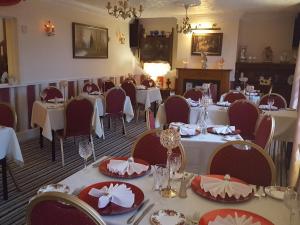 a dining room with white tables and red chairs at Andel Lodge & Restaurant in King's Lynn