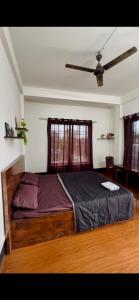 a bedroom with a large bed with a ceiling fan at The Quiet Lantern Homestay in Sibsāgar +3 photos