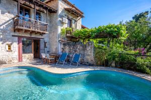 a pool in front of a house with chairs and a table at Forest stone Villa with pool in Kriopigi