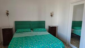 a bedroom with a green bed and a mirror at Casa Renjinella Torre Suda in Torre Suda