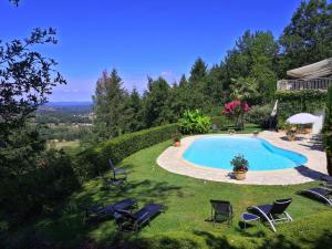 a swimming pool in a yard with lawn chairs at Villa Ric in Saint-Céré