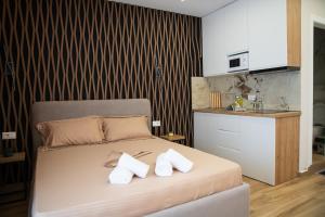 a bedroom with a bed with two pillows and a kitchen at Hersol Skyline in Durrës