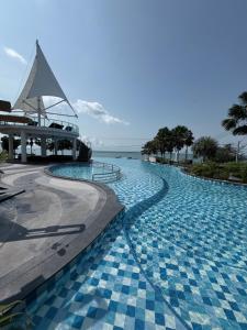 a swimming pool with a building and the ocean at Del Mare Bangsaley condo in Bang Sare