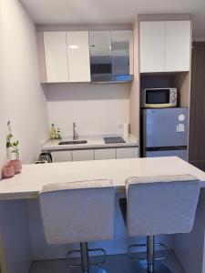 a kitchen with a white counter and two chairs at Del Mare Bangsaley condo in Bang Sare