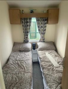 two beds in a small room with a window at Gemini in Heysham