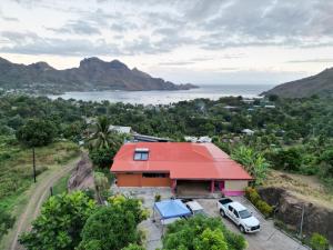 a house with a red roof and a car parked in front at CHEZ ALIZHIA in Nuku Hiva