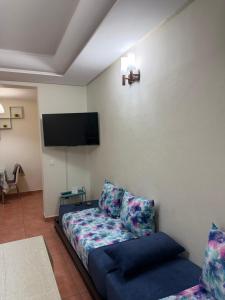 a living room with a couch and a flat screen tv at Appartement calme avec piscine et proche de la plage in Fnidek