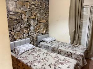 two beds in a room with a stone wall at Appartement calme avec piscine et proche de la plage in Fnidek