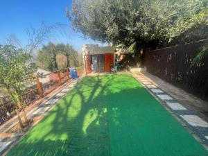 a yard with green grass and a fence at Mafofolozi Lodge in Hartbeespoort