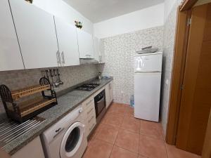 a kitchen with a white refrigerator and a washing machine at Appartement calme avec piscine et proche de la plage in Fnidek