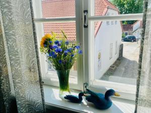 two ducks sitting on a window sill with a vase of flowers at Kauba 6-6 Apartment in Kuressaare