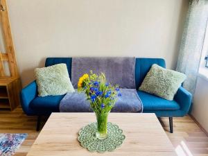 a blue couch with a vase of flowers on a table at Kauba 6-6 Apartment in Kuressaare