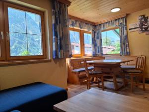 a dining room with a table and chairs and windows at Appartment Sonnenkogel in Holzgau