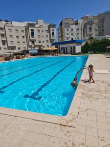 a young child playing in a swimming pool at Appartement calme avec piscine et proche de la plage in Fnidek