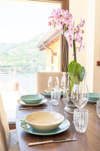 a wooden table with plates and glasses and flowers on it at Luxury Como Lake - Luxury Villa with Infinity Pool in Blevio