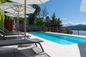 a swimming pool with two lounge chairs and an umbrella at Luxury Como Lake - Luxury Villa with Infinity Pool in Blevio