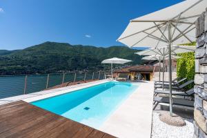 a swimming pool with an umbrella and the water at Luxury Como Lake - Luxury Villa with Infinity Pool in Blevio