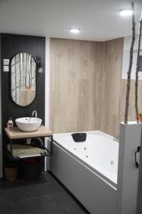 a bathroom with a tub and a sink and a mirror at le Studio Balnéo des Cocons de Mel in Quinssaines