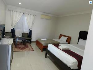 a bedroom with two beds and a table and a chair at Venezia Suites Resort Panglao in Panglao Island