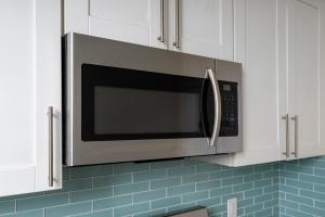 a microwave in a kitchen with white cabinets at SF City Inn free parking on site in Oakland