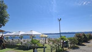 a group of tables and chairs with umbrellas next to the water at Lesa Lake House in Lesa