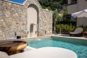 a pool with a wooden tub next to a stone wall at Almyra Living - Adults Only in Agios Gordios