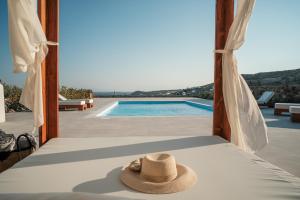 a hat sitting on a bed next to a swimming pool at Elia Horizon Mykonos in Elia Beach +47 photos
